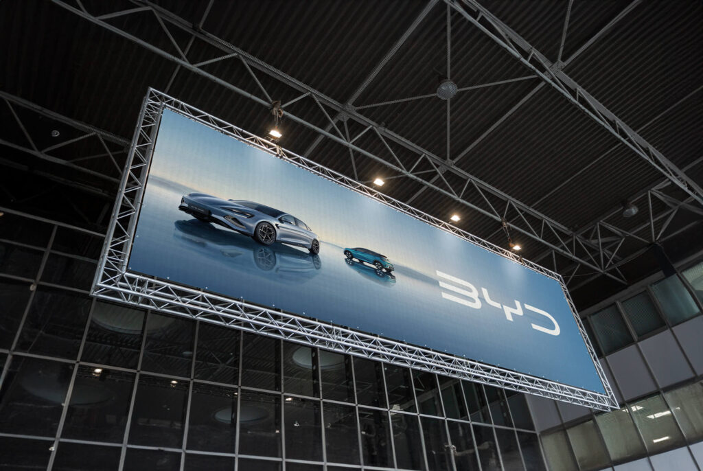 Billboard de la marca de coches eléctricos BYD en España mostrando tres modelos disponibles en el mercado español
