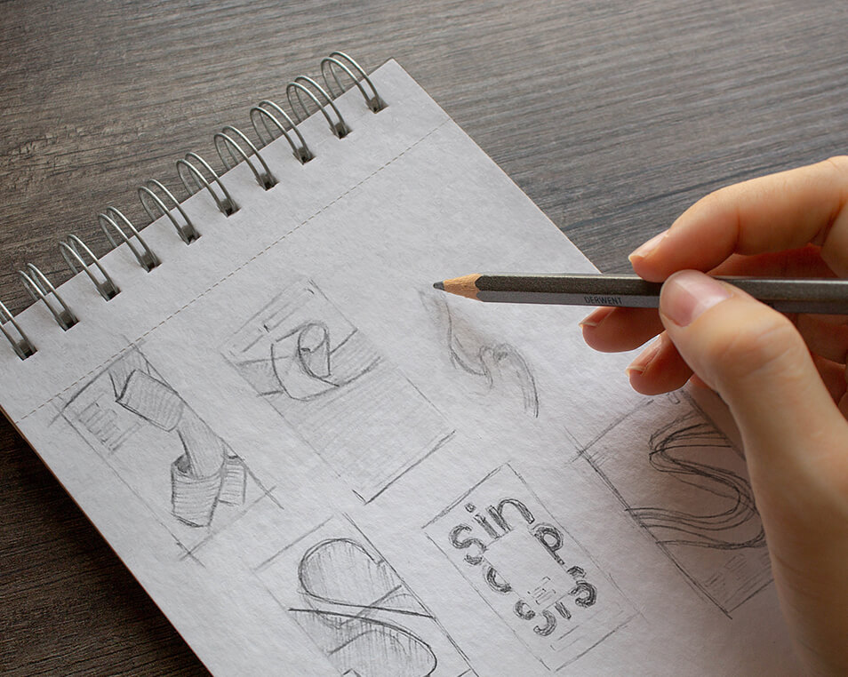 Bocetos a lápiz para la portada de "El libro de las Sinopsis", un libro en un cuaderno de espiral, destacando la creatividad en el diseño de portadas